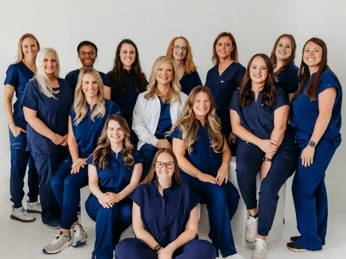 A group photograph of Athens Dental Associates team members in navy scrubs, standing and seated.