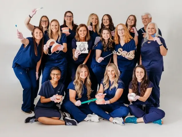 A group photograph of Athens Dental Associates team members in navy scrubs.